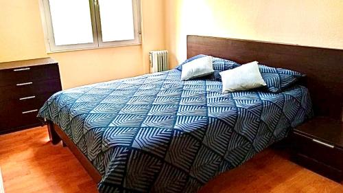 a bedroom with a bed with a blue and white comforter at Acogedor piso en Puertollano in Puertollano