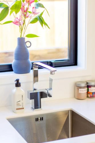 a kitchen sink with a vase and a window at Gateway to Hagley park - 2 bed w/carpark in Christchurch