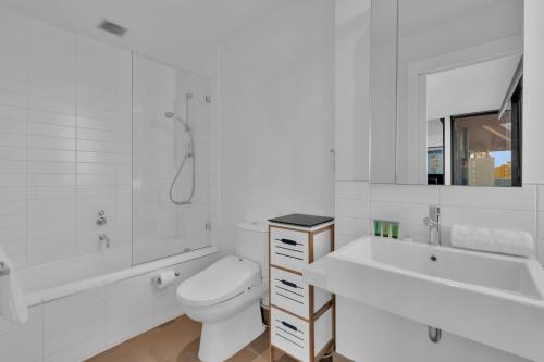 Tranquil 1-Bed Haven with Swimming Pool by CBD في ملبورن: حمام أبيض مع مرحاض وحوض استحمام ومغسلة