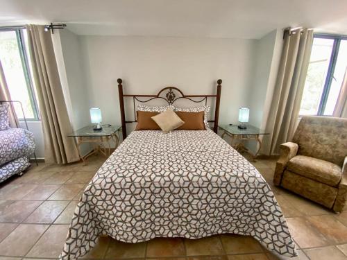 a bedroom with a bed and a chair and windows at Habitacion Grande Casa las Trojes in Aguascalientes