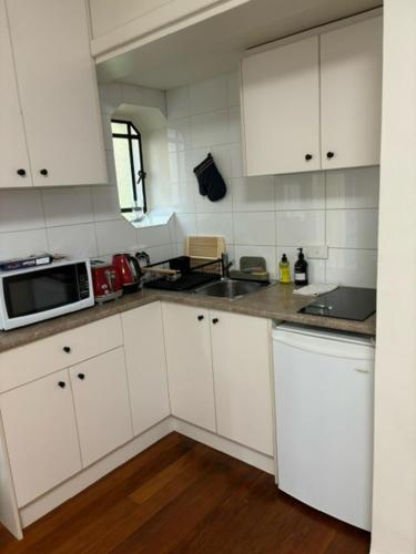 a kitchen with white cabinets and a microwave at Regents Gate 53 in Melbourne
