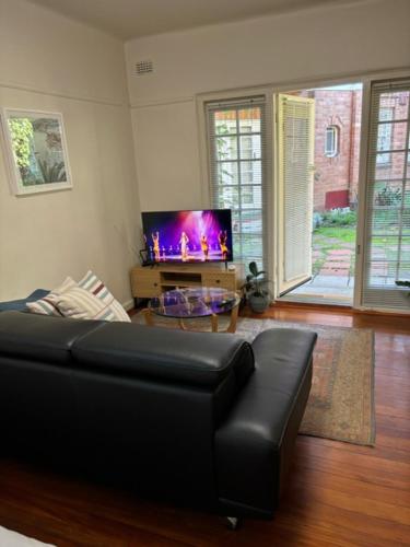 a living room with a black couch and a tv at Regents Gate 53 in Melbourne
