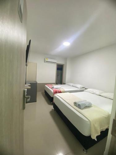 a room with two beds and a television in it at Hostal Tamaca Beach in Puerto de Gaira