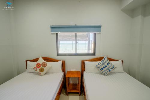 2 Einzelbetten in einem kleinen Zimmer mit Fenster in der Unterkunft Sea House in Ấp Bình Hưng