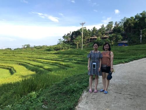 two women standing on a road next to a field at Pù Luông Sala Homestay in Hương Bá Thước