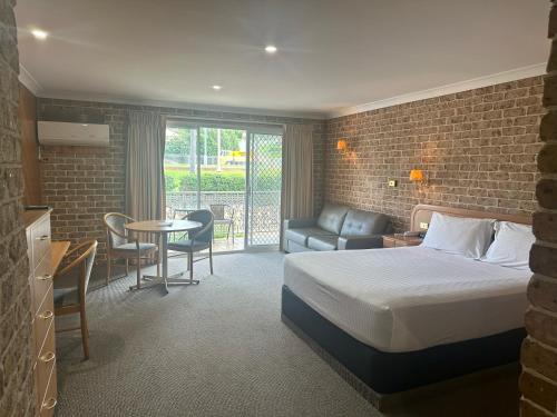 a hotel room with a bed and a table and chairs at The Hermitage Motel - Campbelltown in Campbelltown