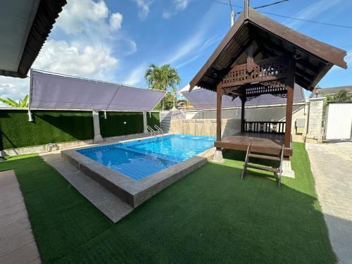 a swimming pool with a gazebo and a chair at Mawar 23 Chendering with Private Pool in Kuala Terengganu