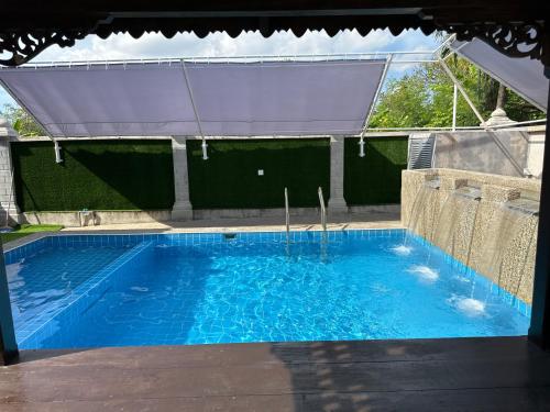 a large blue swimming pool with a canopy at Mawar 23 Chendering with Private Pool in Kuala Terengganu