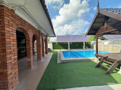 a brick house with a swimming pool in a yard at Mawar 23 Chendering with Private Pool in Kuala Terengganu