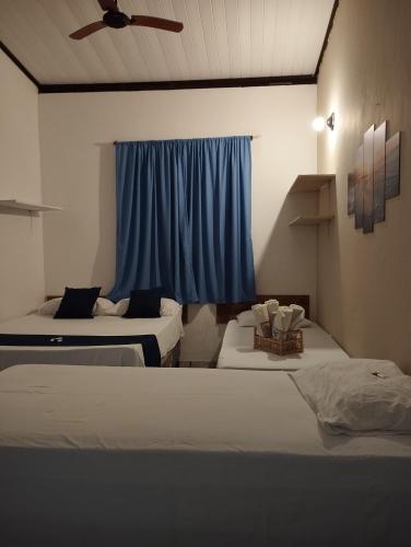 a bedroom with two beds and a blue curtain at Pousada Ray Sol - Centro Arraial d Ajuda in Porto Seguro