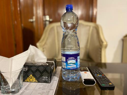 una bottiglia d'acqua su un tavolo accanto a un telecomando di E Lodge a Islamabad
