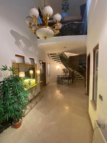 um corredor com um lustre e escadas num edifício em E Lodge em Islamabad