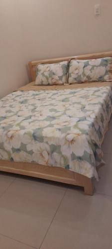 a bed with a comforter with flowers on it at Nhà nghỉ Kim Cương in Rach Gia