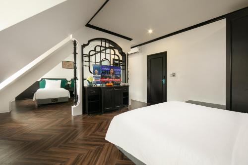 a bedroom with a white bed and a tv at Elegant Boutique Hotel Ha Long in Ha Long