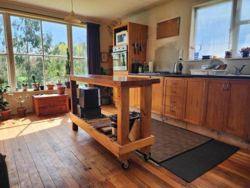 a kitchen with a wooden table in the middle at Cabin with hottub at homestay in Karitane