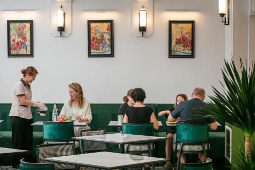 a group of people sitting at tables in a restaurant at Elegant Boutique Hotel Ha Long in Ha Long