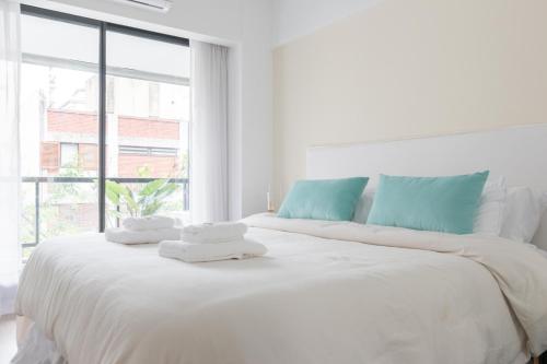 - une chambre blanche avec un grand lit et des serviettes dans l'établissement Fliphaus Zapiola 2300 'b' - 1 Bd Belgrano, à Buenos Aires