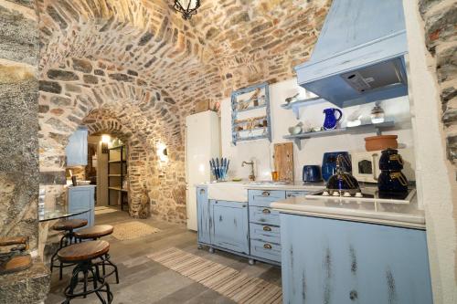 a kitchen with blue cabinets and a brick wall at Byzantine Home in the Castle in Mesta