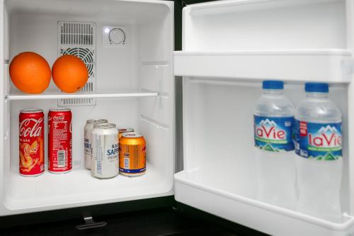 an open refrigerator with drinks and oranges in it at Elegant Boutique Hotel Ha Long in Ha Long