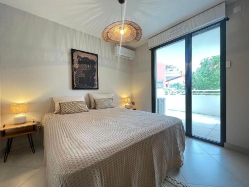 une chambre avec un lit et une grande fenêtre dans l'établissement Appartement de standing 3 pièces avec clim, garage double, proche plages et commerces à Sète - FR-1-338-572, à Sète