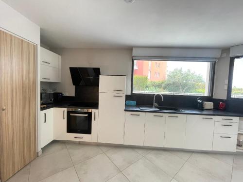 une cuisine vide avec des placards blancs et une fenêtre dans l'établissement Appartement de standing 3 pièces avec clim, garage double, proche plages et commerces à Sète - FR-1-338-572, à Sète