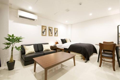 a bedroom with a bed and a couch and a table at プロスパービル 2B in Naha