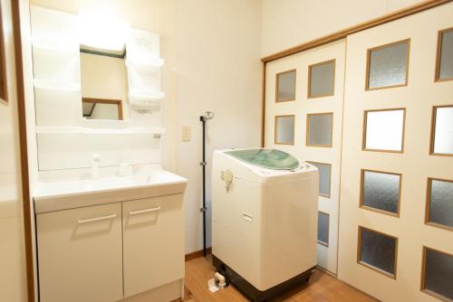 a bathroom with a sink and a mirror and a refrigerator at 富江宿 in Tomie