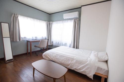 a bedroom with a bed and a desk and windows at 富江宿 in Tomie