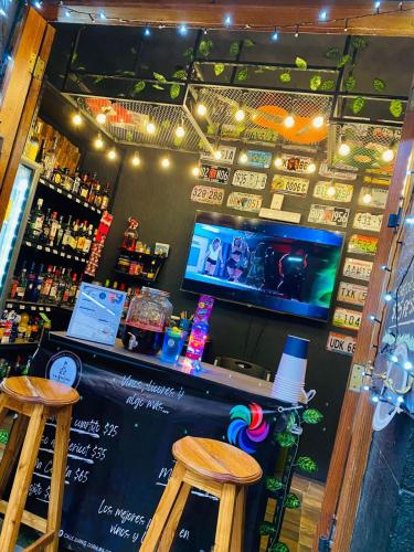 a bar with two wooden stools and a tv at Campestre La Ninfa in Huasca de Ocampo
