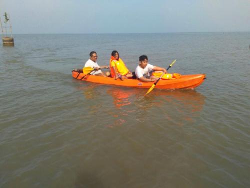 three people in an orange kayak in the water at Villa Gardenia Pantai Jepara in Jepara