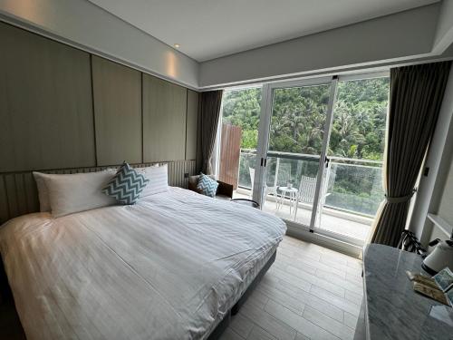 a bedroom with a large bed and a large window at Hayata Hotel in Hengchun South Gate