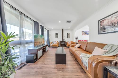 a living room with a couch and a tv at Melbourne Airport Pet friendly Guest House in Melbourne