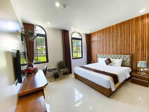 um quarto com uma cama, uma secretária e uma televisão em An Hotel Ha Long em Ha Long