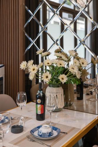 a table with a vase of flowers and a bottle of wine at Y Homestay Đà Nẵng Gần Sân Bay và trung tâm in Da Nang