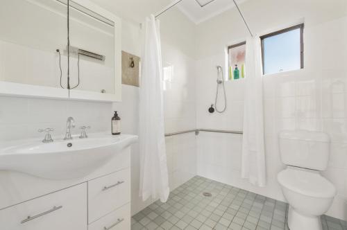 a white bathroom with a toilet and a sink at Dusties 5 Pacific Street in South West Rocks