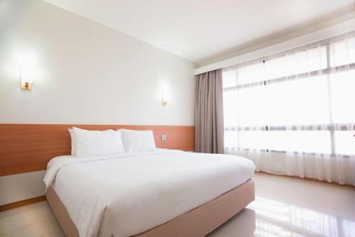 a bedroom with a white bed and a large window at Pinnacle Lumpinee Park Hotel in Bangkok