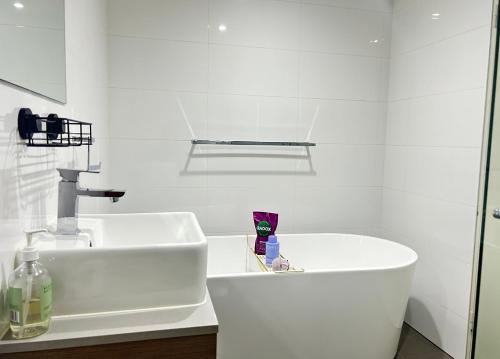 Baño blanco con lavabo blanco y lavabo en Drummoyne Apartment, en Sídney