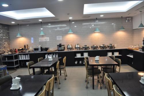 un restaurante con mesas y sillas y una cocina en HOUND Hotel Sangmu en Gwangju