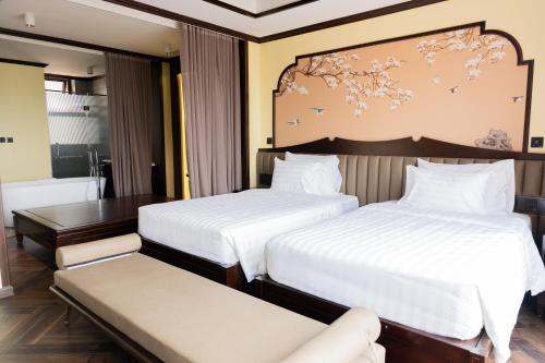 a hotel room with two beds and a bench at Legacy Hill Resort & Villas in Hòa Bình