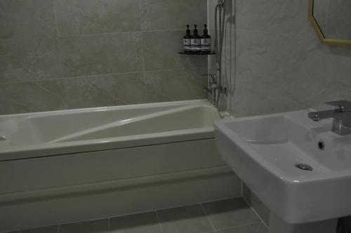 a bathroom with a sink and a bath tub and a sink at HOUND Hotel Sangmu in Gwangju