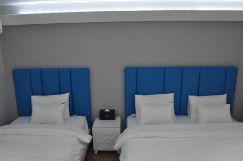 two beds with blue headboards in a room at HOUND Hotel Sangmu in Gwangju