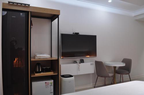 a room with a tv and a table and chairs at HOUND Hotel Sangmu in Gwangju