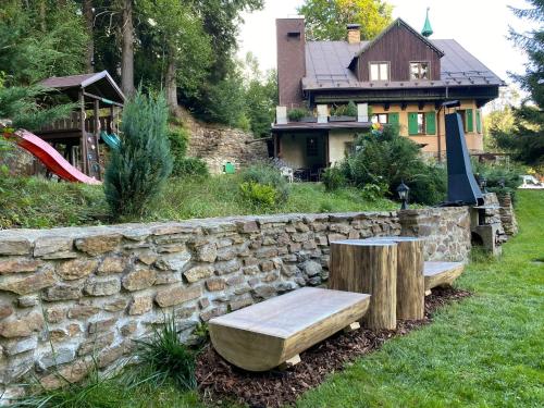 a stone wall with a bench in front of a house at Alba Apartmany Železná Ruda in Železná Ruda