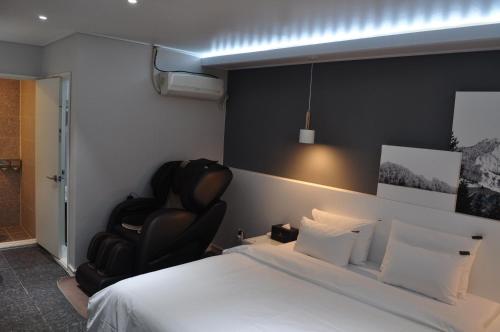 a bedroom with a bed and a black chair at HOUND Hotel Sangmu in Gwangju