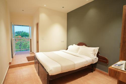 a bedroom with a bed and a large window at Rasha residency in Kalpetta