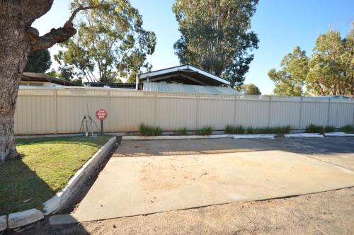 a stop sign in front of a white fence at Riverview Holiday Apartment 112 - Kalbarri WA in Kalbarri