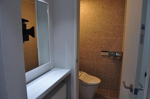 a bathroom with a toilet and a sink and a mirror at HOUND Hotel Sangmu in Gwangju