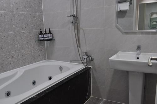 a bathroom with a bath tub and a sink at HOUND Hotel Sangmu in Gwangju