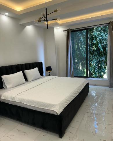 a bedroom with a large bed with a large window at REOs Smart Haven with Pool in Oblogo
