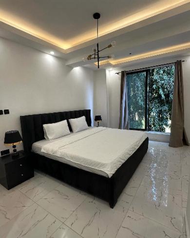 a bedroom with a large bed and a large window at REOs Smart Haven with Pool in Oblogo